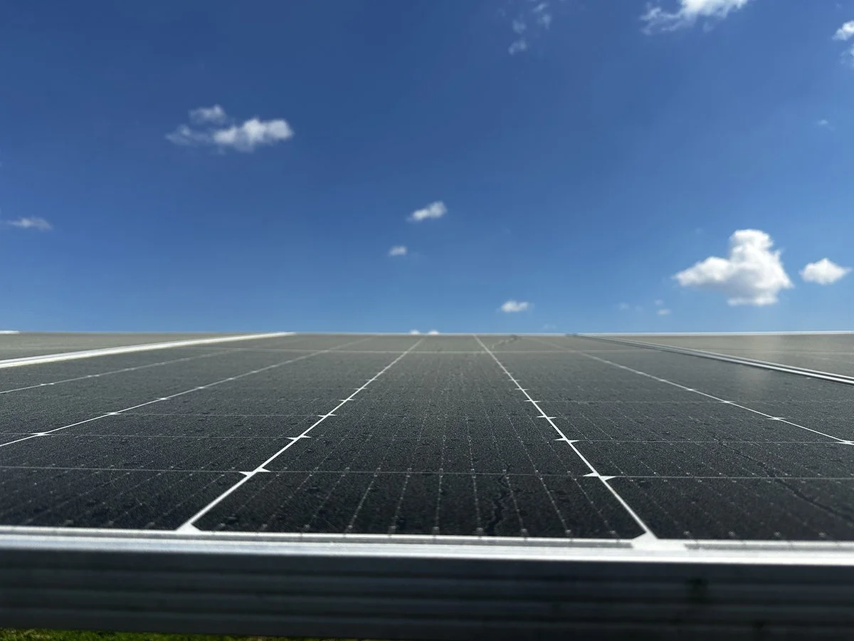 Close-up of a solar panel under a blue sky with a few clouds.