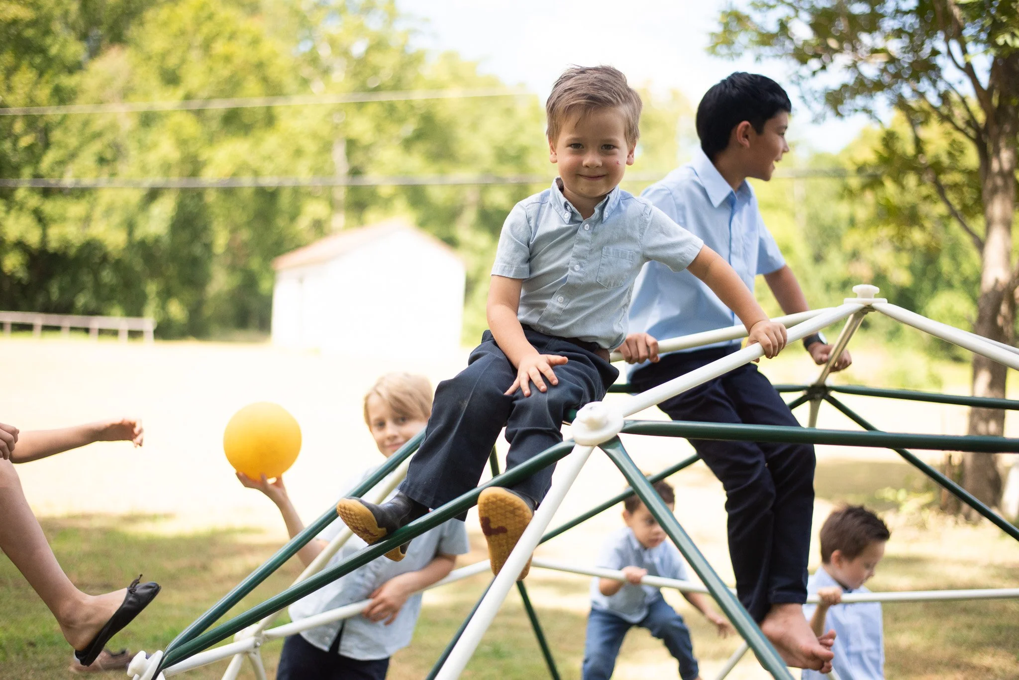 Children playing on a metal jungle gym outdoors in a park on a sunny day.