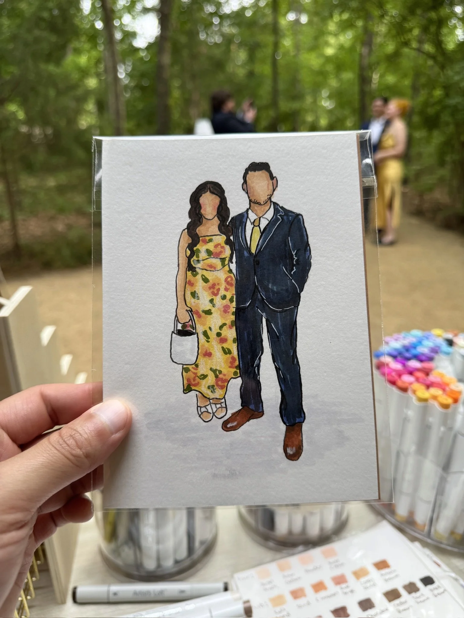 Illustration of a man and woman dressed formally, holding hands. The woman is wearing a yellow floral dress and carrying a white purse, the man is in a dark blue suit with a yellow tie. Live guest portraits and watercolor illustrations of guests.