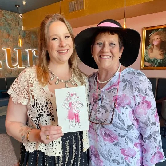 Two guests at Auberge Resorts Collection in Napa holds up an illustration created by Vignette Du Vin