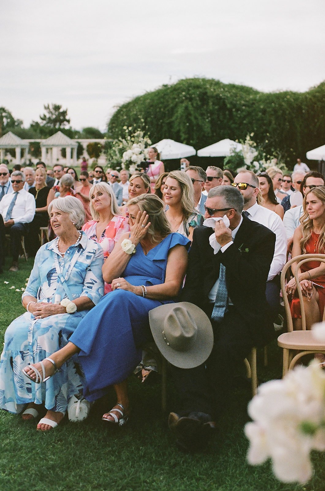Guests crying at a Merv Griffin Estate wedding ceremony with outdoor green garden party decor designed by COJ Events