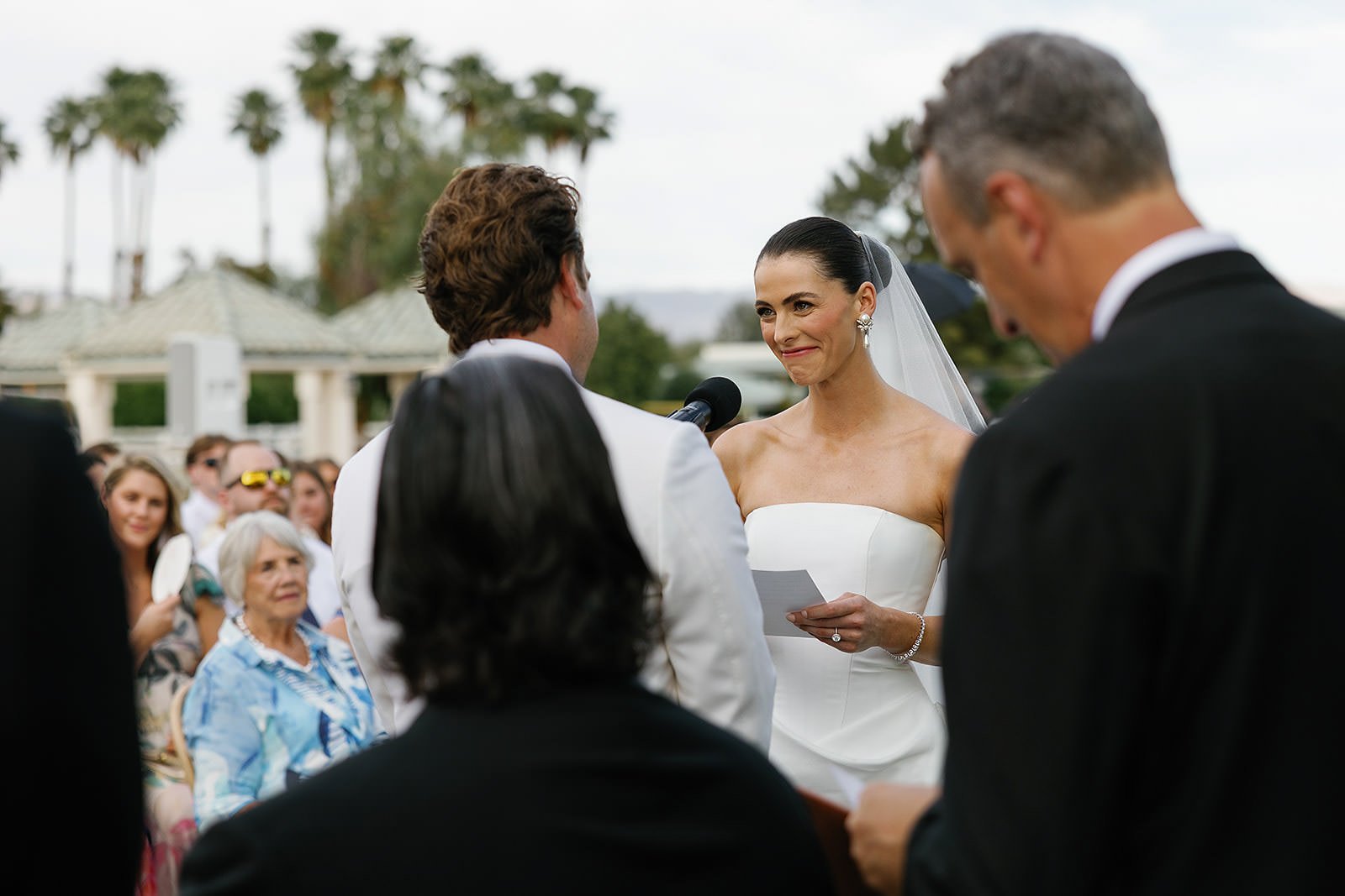 Vows at a Merv Griffin Estate wedding ceremony with outdoor green garden party decor designed by COJ Events