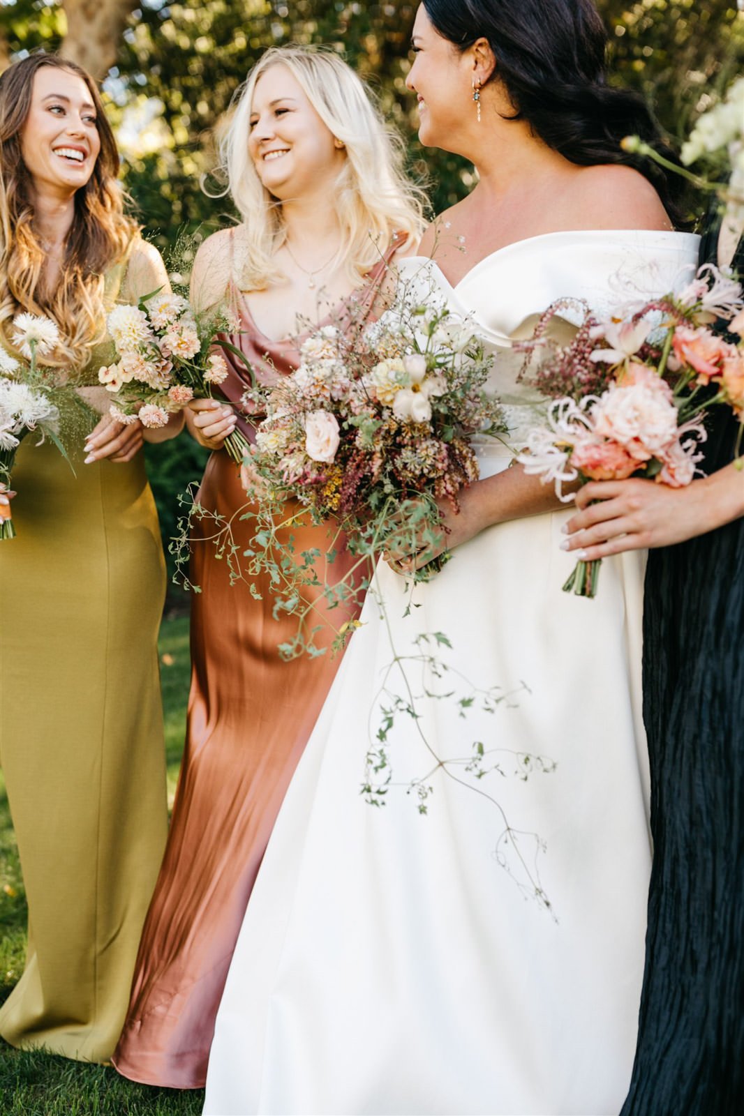 Bride and bridesmaids casual portrait while holding bouquets of subtle warm-colored roses with a woodland vibe on the grounds of The Madrona -Planned by COJ Events-Palm Springs Destination Wedding