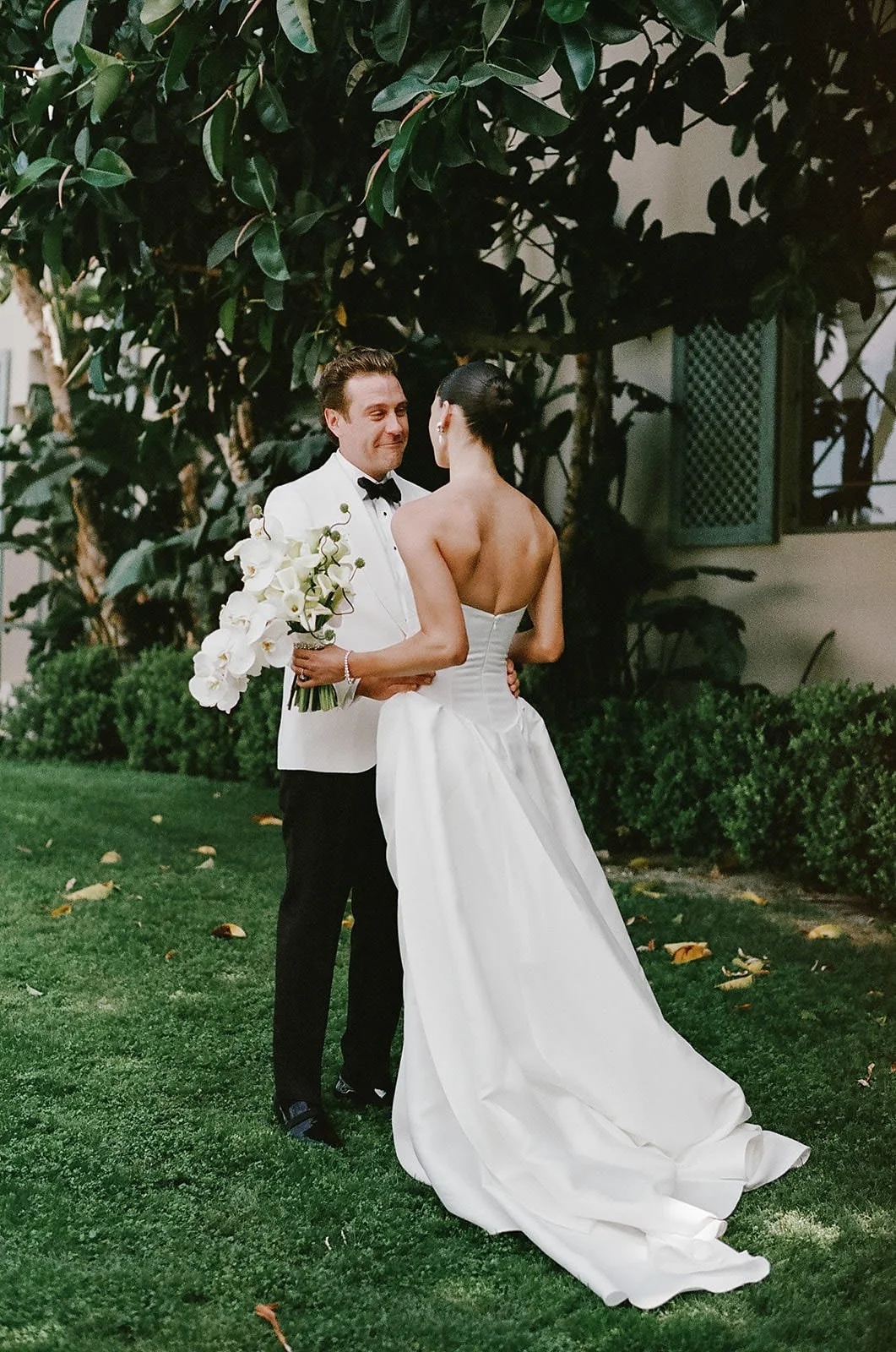 Bride and groom's first look at a Merv Griffin Estate wedding with outdoor green garden party decor designed by COJ Events