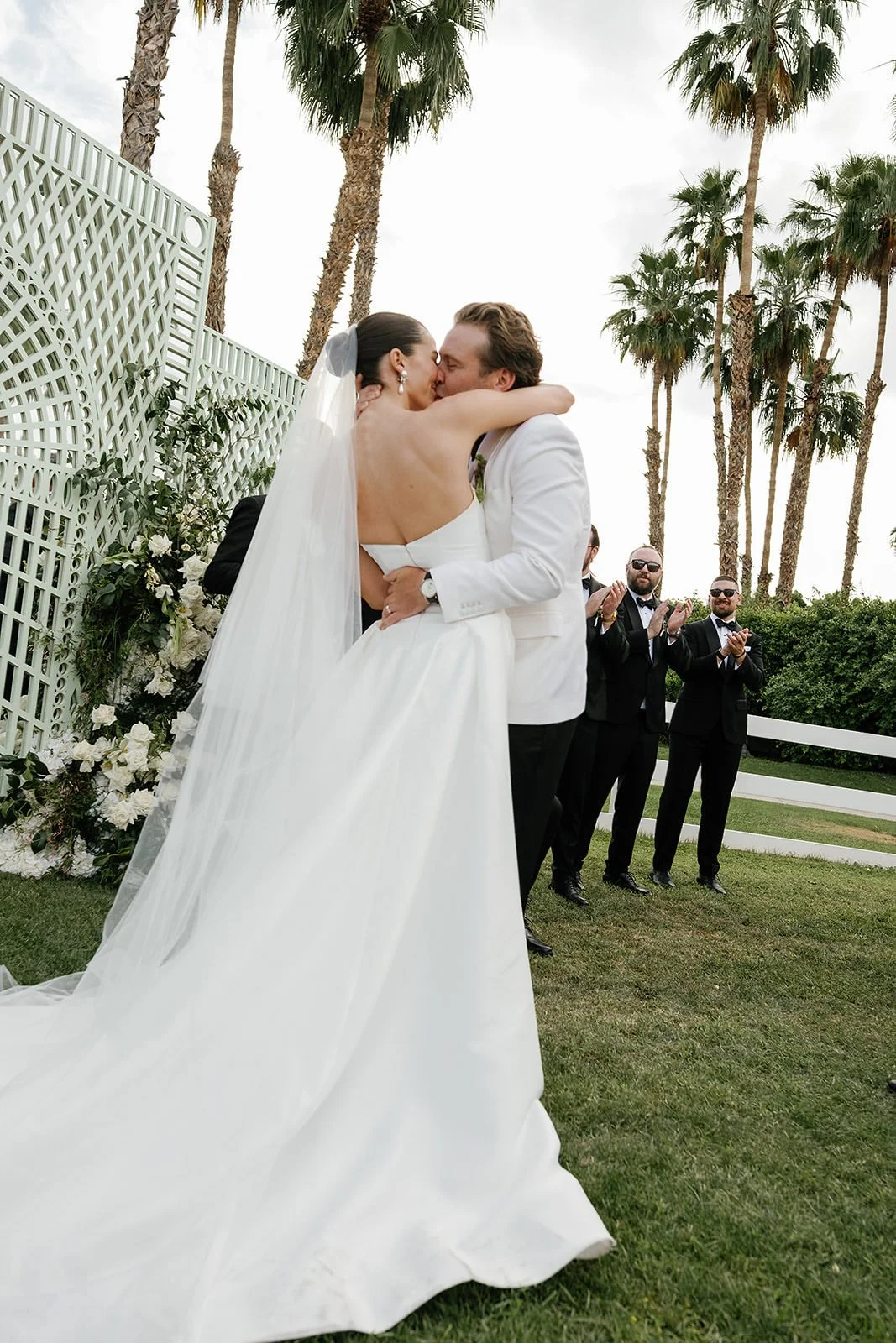 The first kiss at a Merv Griffin Estate wedding ceremony with outdoor green garden party decor designed by COJ Events