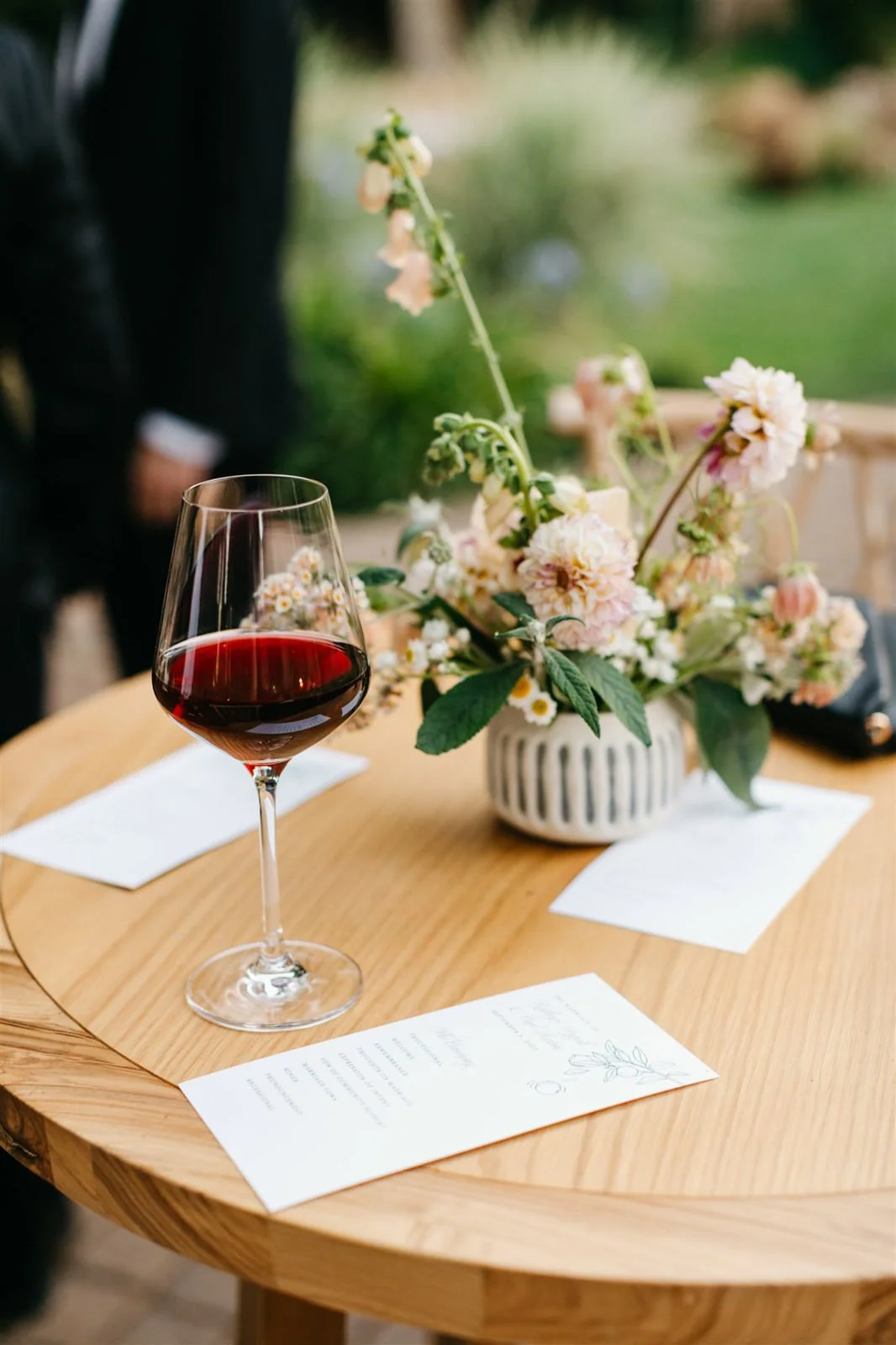 Woodland vibe florals and a glass of red wine on cocktail hour tables on the grounds of The Madrona -Planned by COJ Events-Palm Springs Destination Wedding