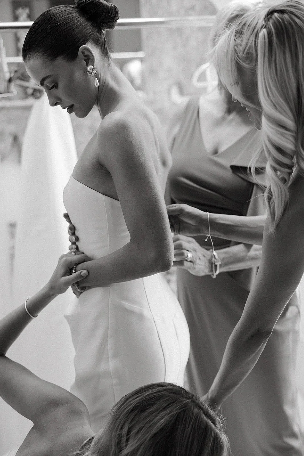 Bride getting dressed at a Merv Griffin Estate wedding with outdoor green garden party decor designed by COJ Events