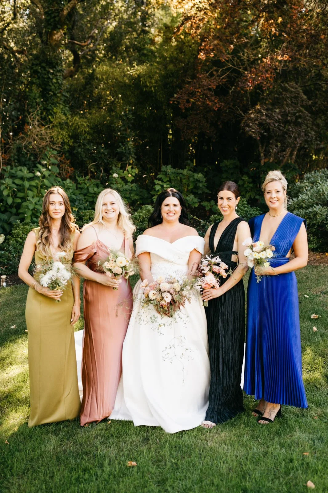 Bride and bridesmaids portrait while holding bouquets of subtle warm-colored roses with a woodland vibe on the grounds of The Madrona -Planned by COJ Events-Palm Springs Destination Wedding