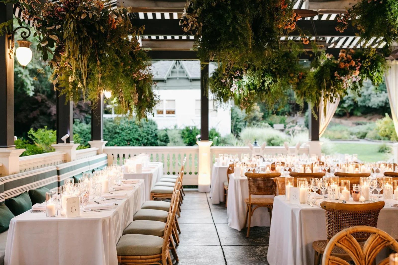 Couple's candlelit reception tables with white linens under a wooden pergola of lush green vines-Planned by COJ Events-Palm Springs Destination Wedding