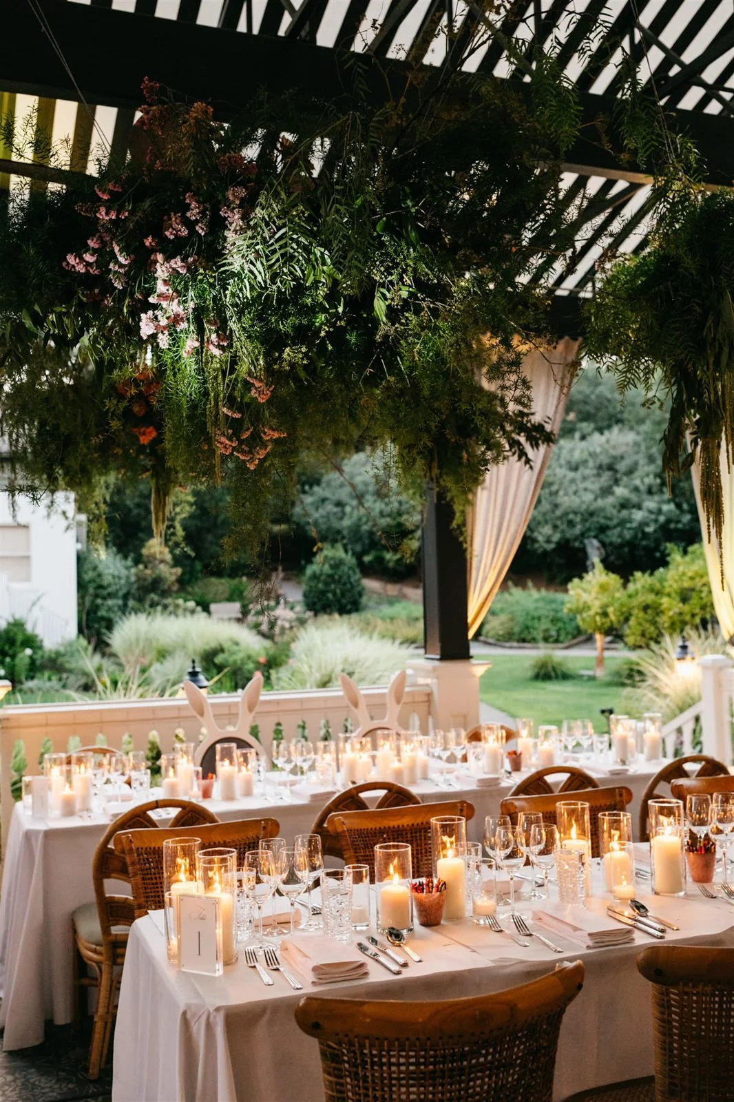 Couple's candlelit reception tables with white linens under a wooden pergola of lush green vines-Planned by COJ Events-Palm Springs Destination Wedding