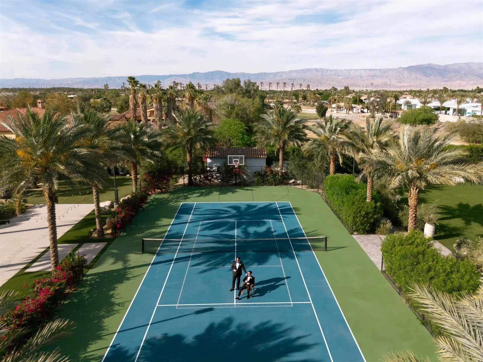 Tennis court portrait of two grooms at Cache Estate Wedding in Indio, CA, by Palm Springs wedding planner COJ Events