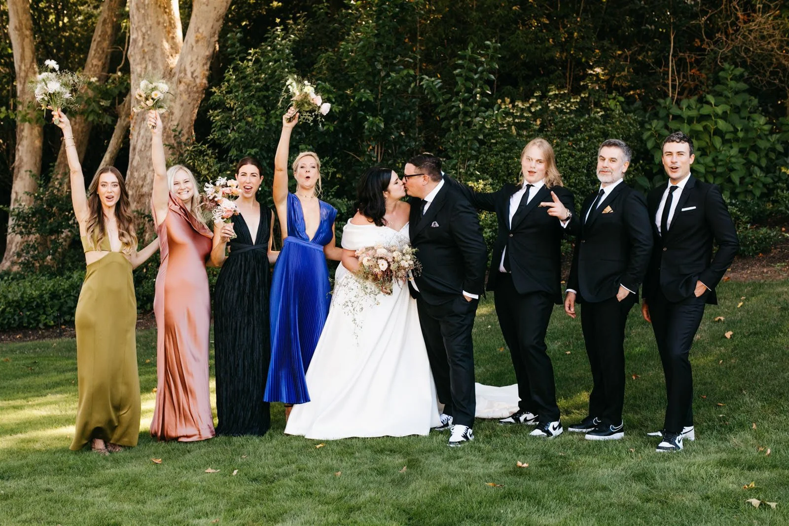 Fun bridal party portrait while holding bouquets of subtle warm-colored roses with a woodland vibe on the grounds of The Madrona -Planned by COJ Events-Palm Springs Destination Wedding