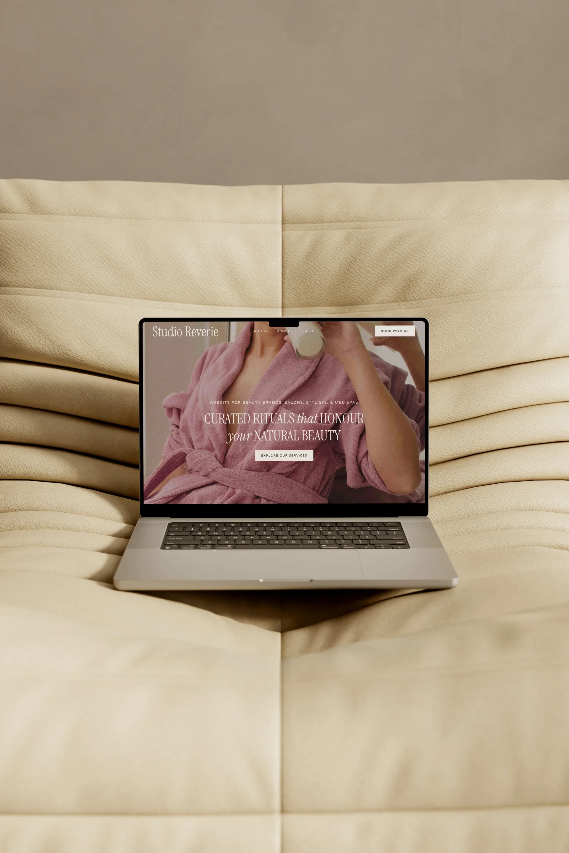 Laptop displaying an editorial beauty studio homepage with a soft feminine hero image