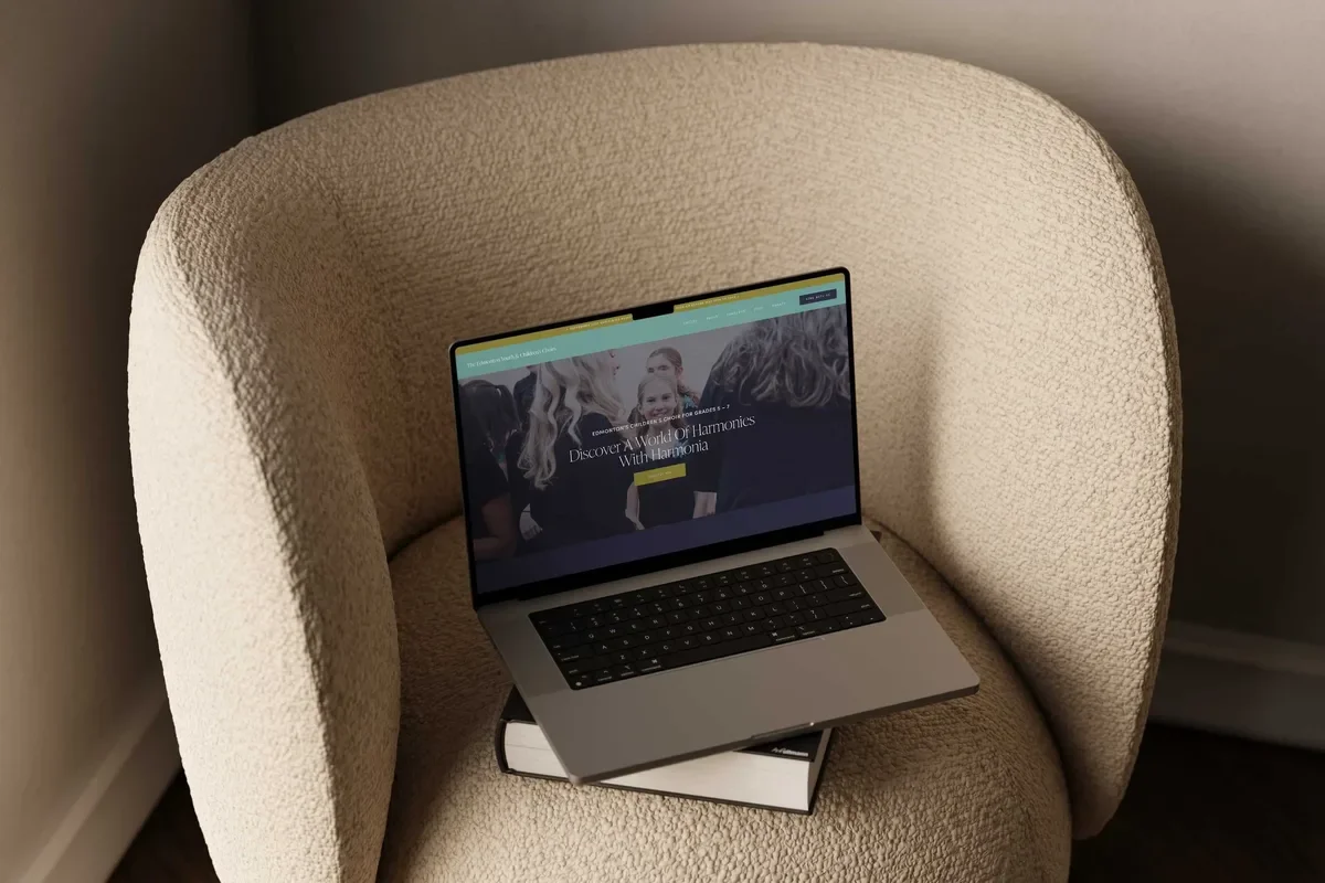 Laptop on a bouclé armchair showing the Harmonia children’s choir page for Grades 5 to 7