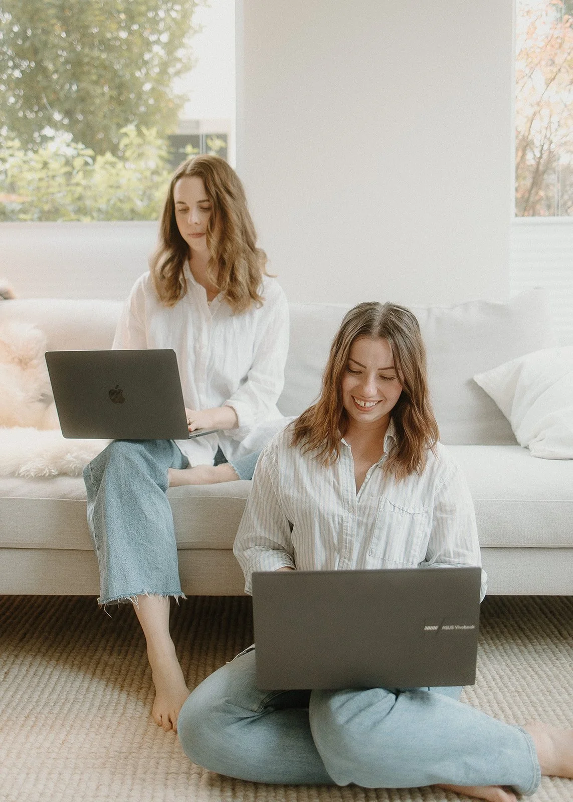 isobel griffin and samara bortz sitting in a living room working on websites on their laptops