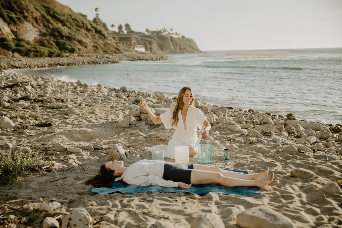 Ocean therapy practitioner leading a sound bath session on a California beach