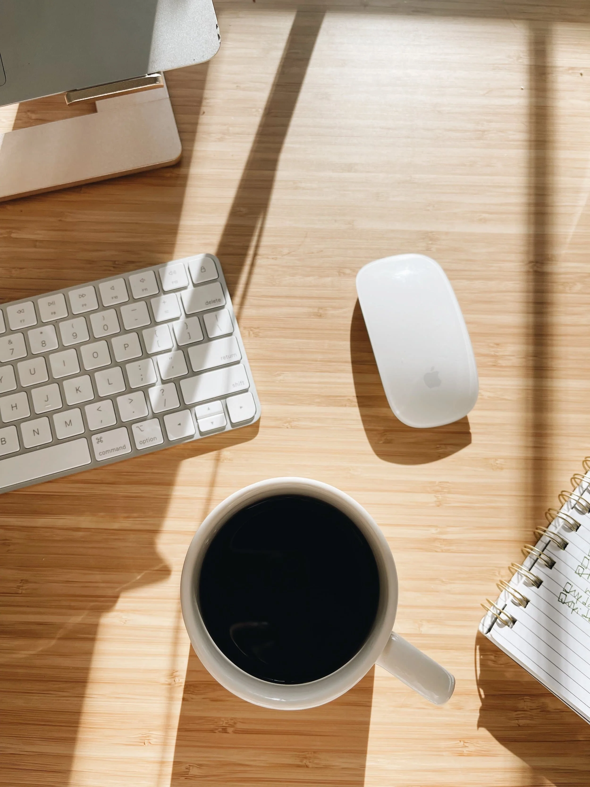 A full coffee cup sitting next to a mac keyboard and mouse