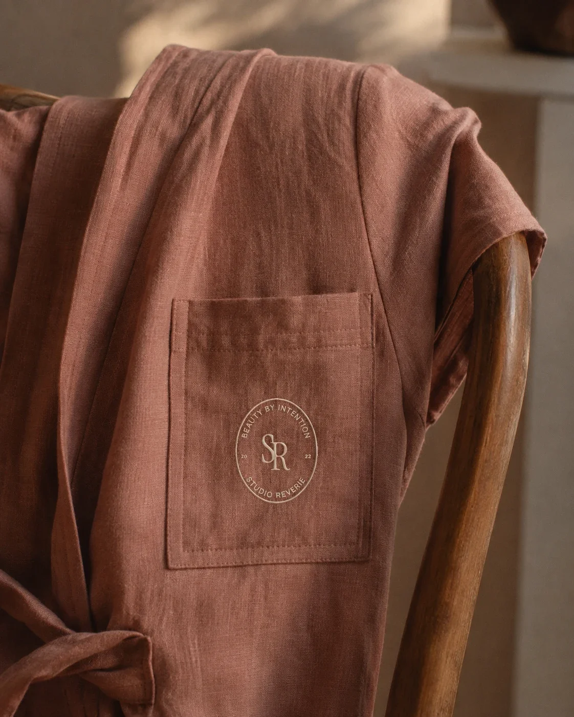 Close-up of an embroidered beauty studio logo patch on a linen robe pocket
