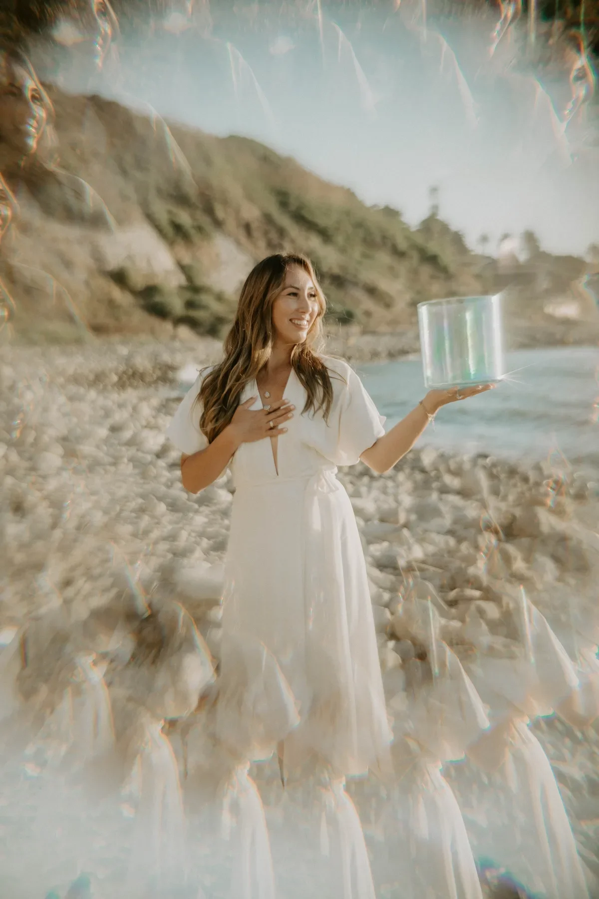 Ocean therapy practitioner holding a crystal singing bowl on a California beach