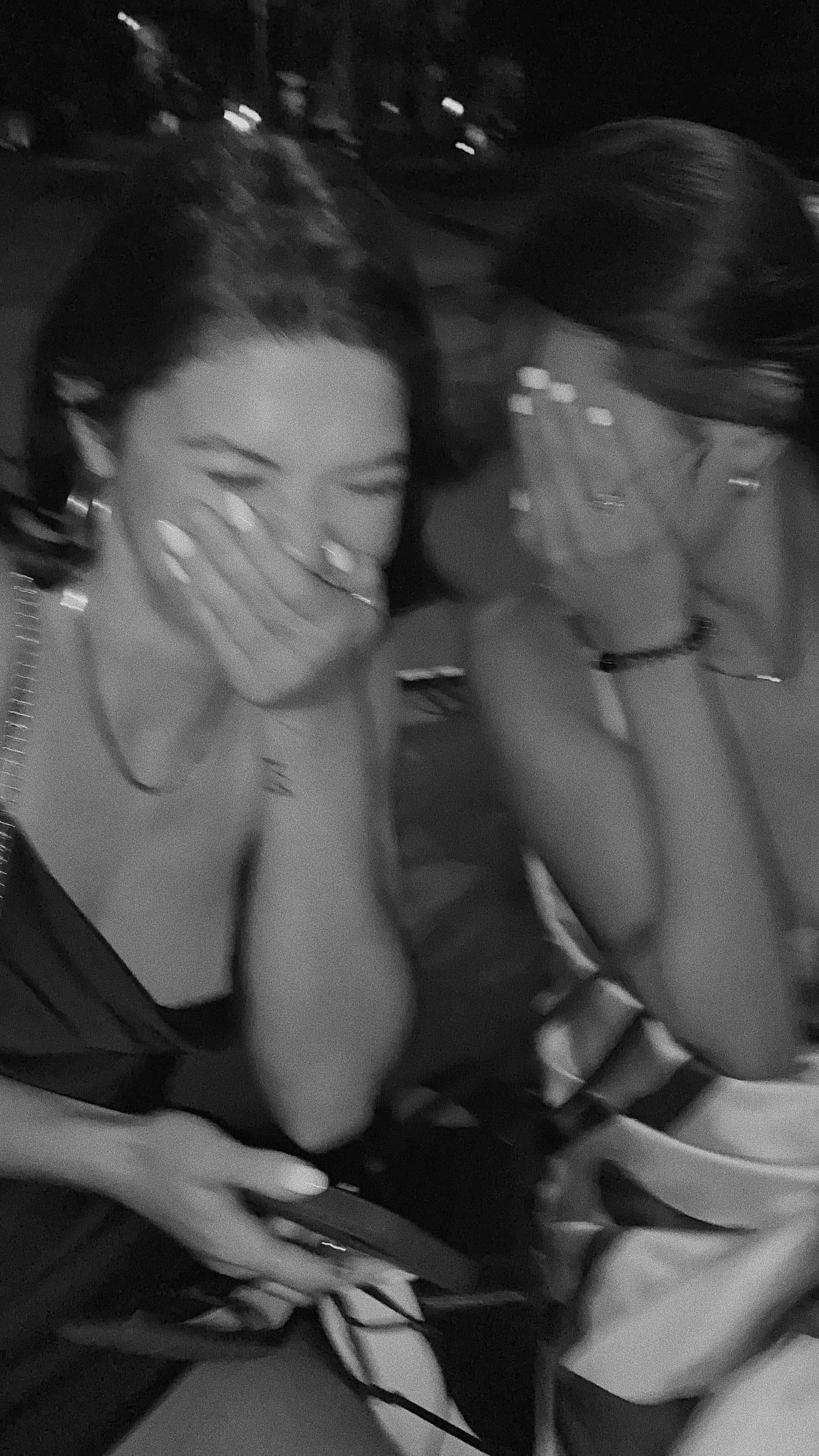 a black and white photo of two friends giggling and covering their faces