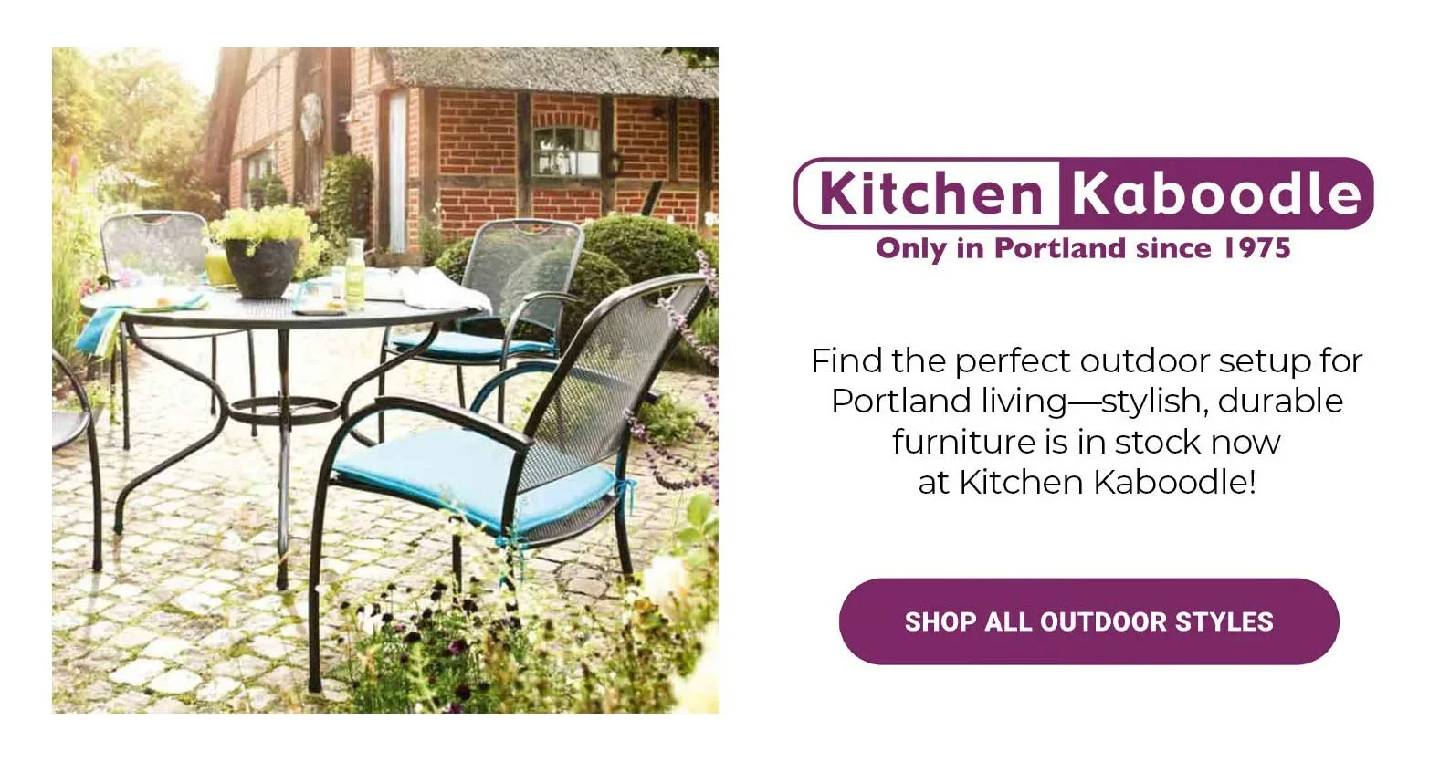 Outdoor patio with a round metal table, four chairs with blue cushions, and a potted plant, in front of a brick house with a garden.