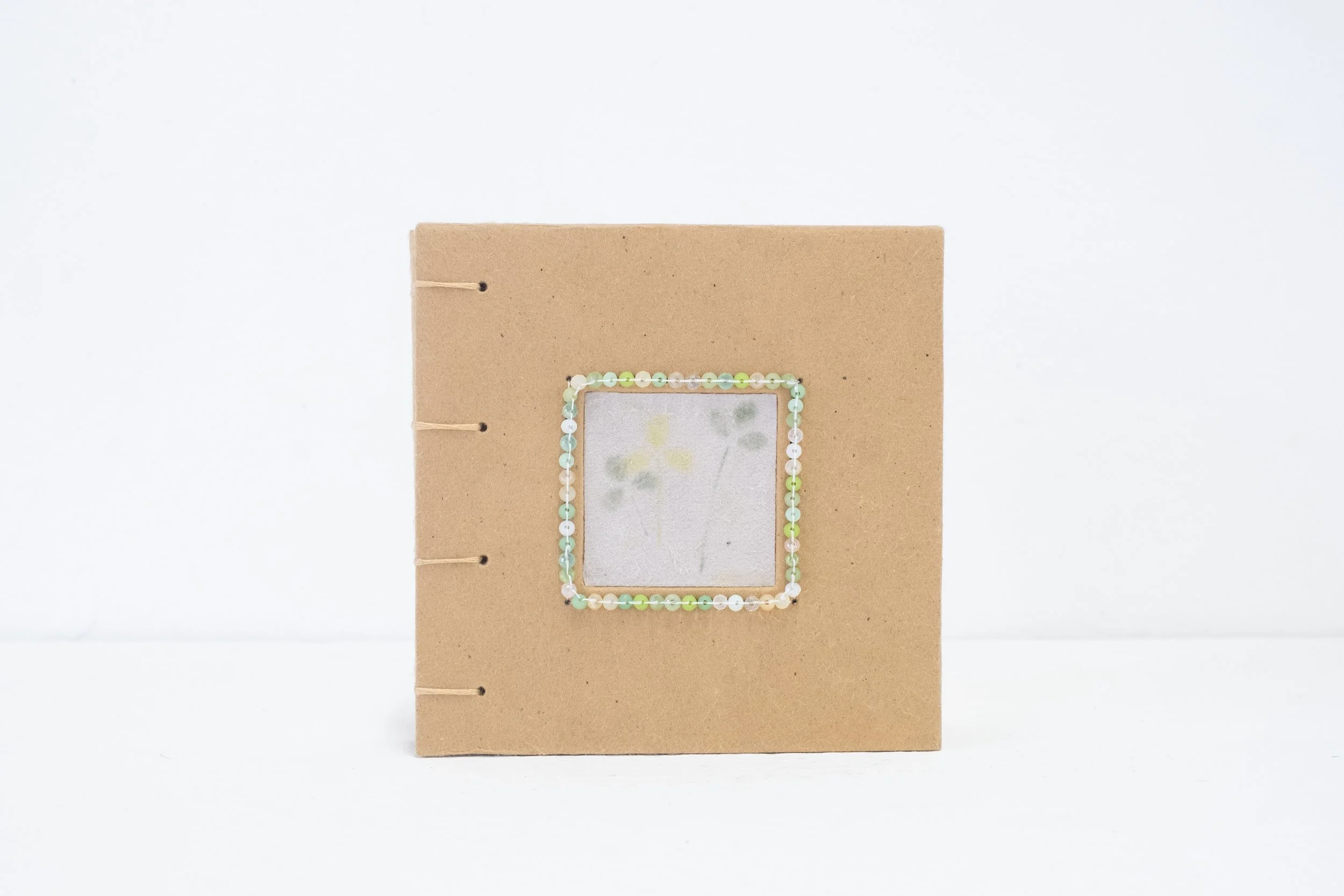 eska board; cotton fibre; abaca fibre; marigold, tango cosmos, and coreopsis petals; shell beads; crystal beads; pencil crayons; embroidery thread (various sizes)