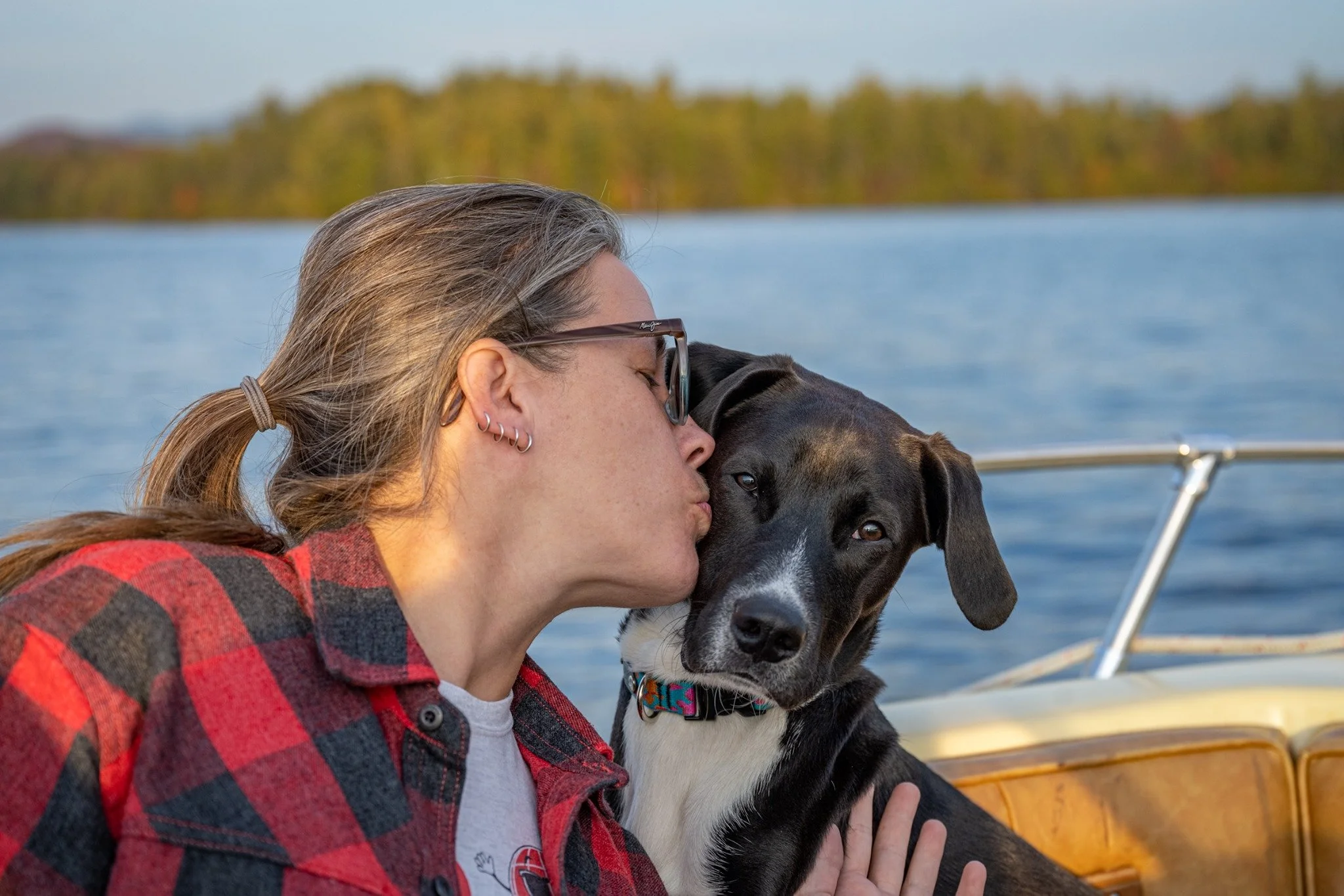 Shelly Cihan, Rooted Rock Marketing founder, kissing her dog Nico on a boat on Lower Saranac Lake.