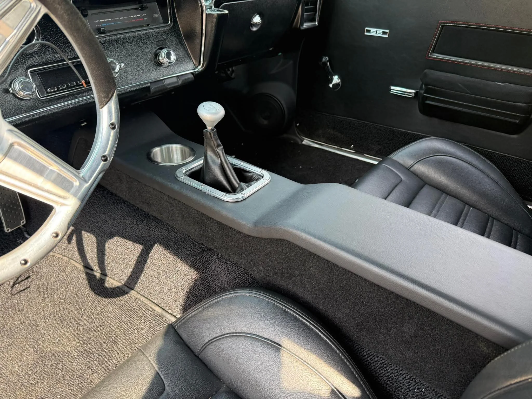 Interior of a vintage car with black leather seats, gear shift, and classic dashboard.