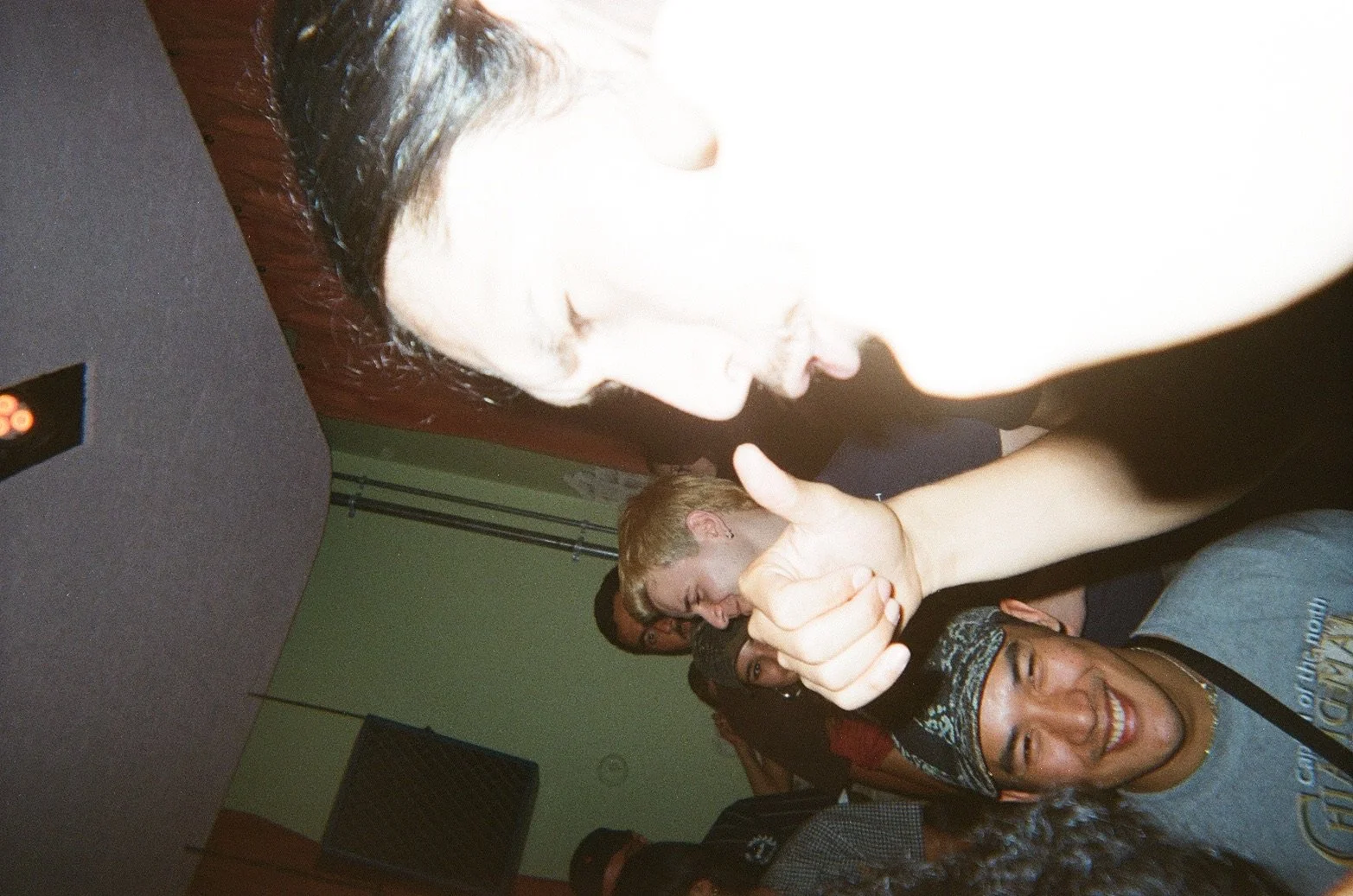 Group of young people smiling, giving thumbs up, at a social gathering.