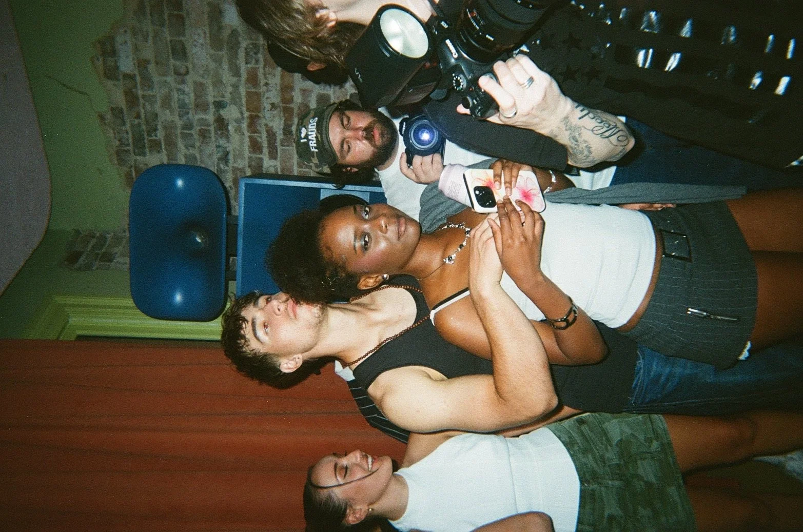 A group of five diverse young adults posing for a photo at a social gathering.