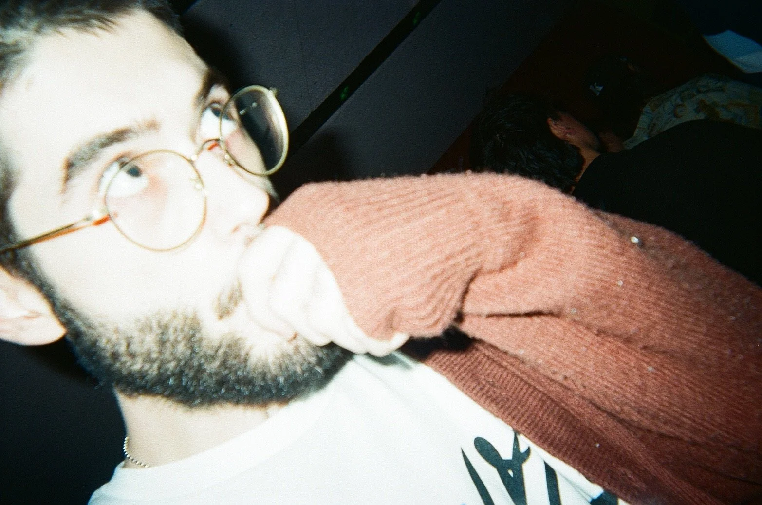A man with glasses and a beard, holding a sock near his face, in a close-up portrait.