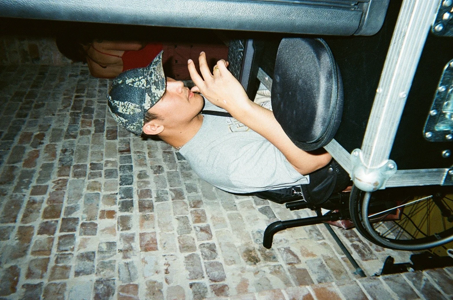 A young man sitting in a wheelchair, wearing a baseball cap and a gray t-shirt, is drinking from a glass.