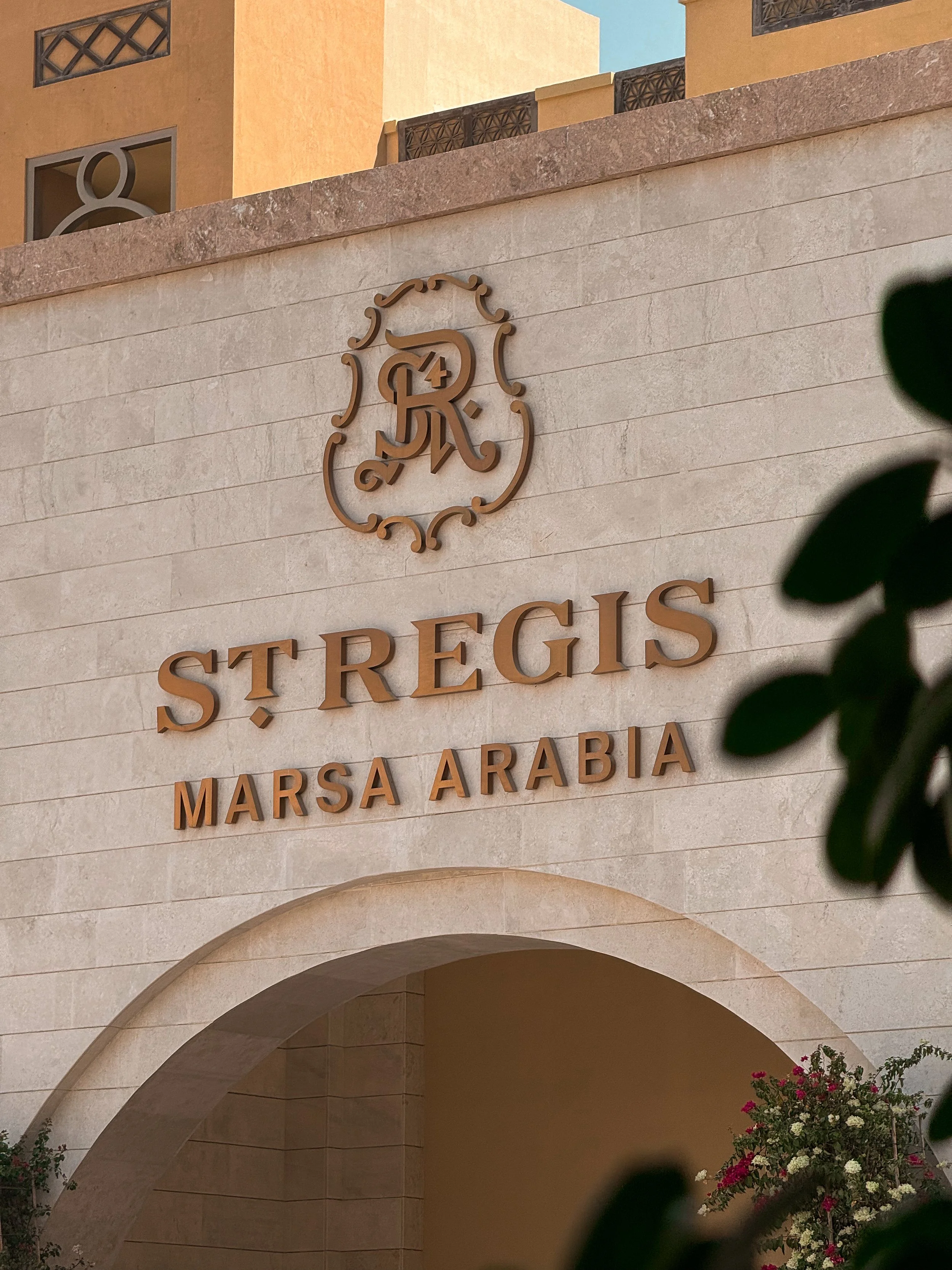 Sign on building reading 'St. Regis, Marsa Arabia' with logo above and decorative archway below.