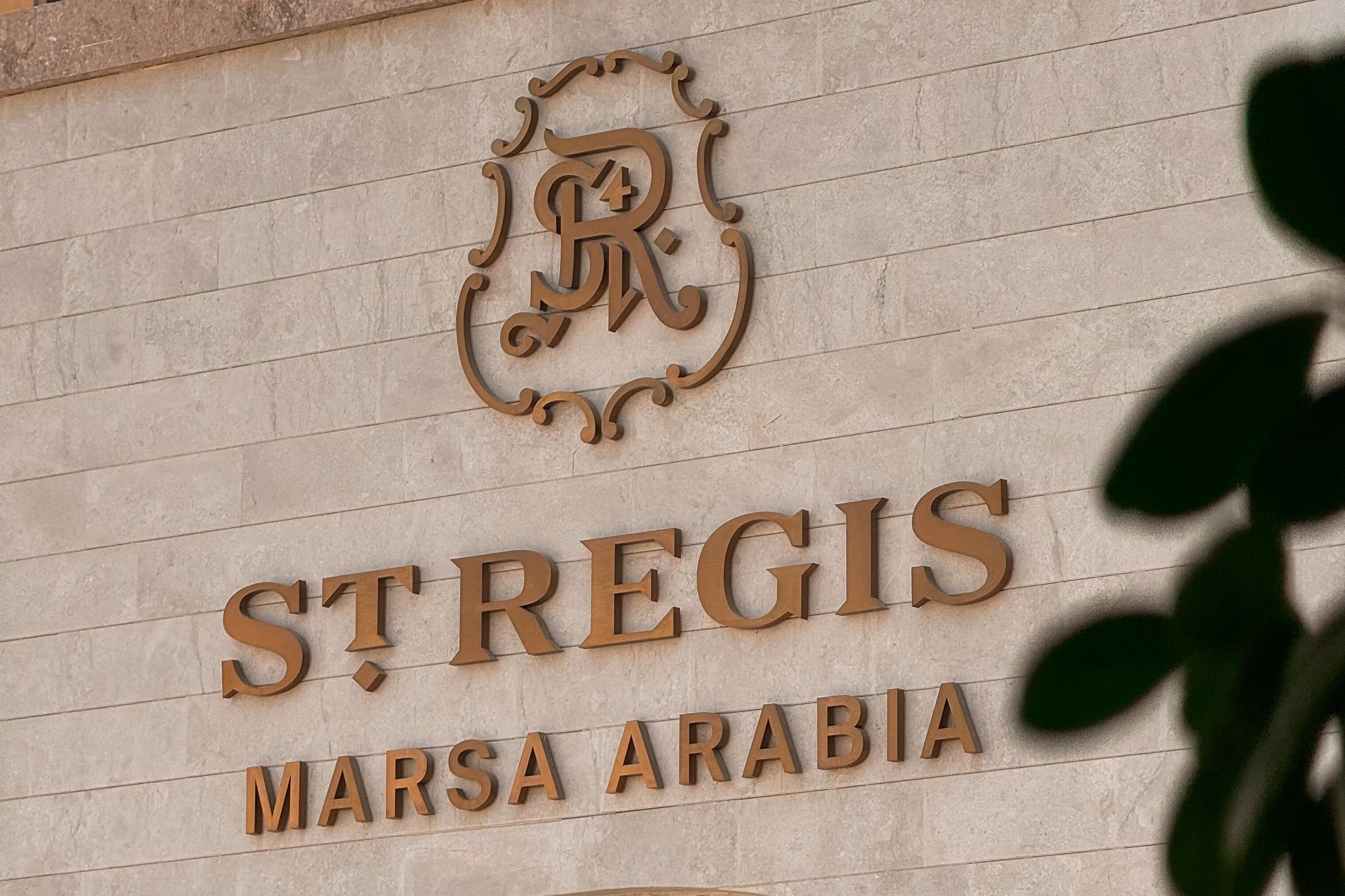 Sign on a wall displaying the logo and name of St. Regis Marsa Arabia, 