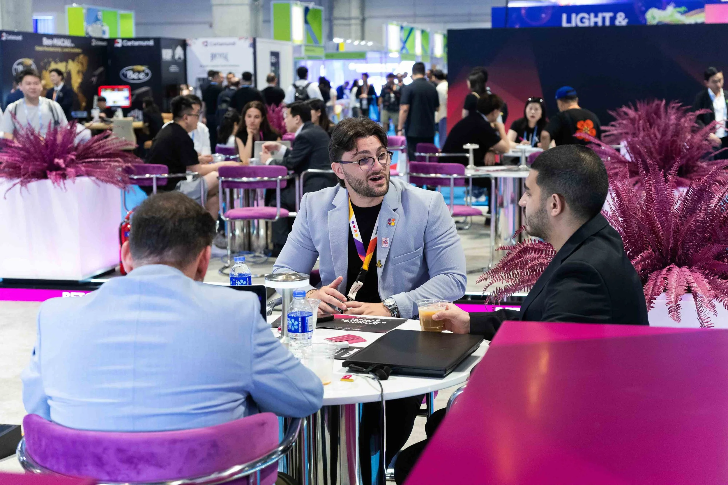 Exhibitor business meeting photography in Macau showing client conversations during a trade show. 澳門參展商商務會面攝影，紀錄展會期間的客戶洽談、攤位交流及商務互動。