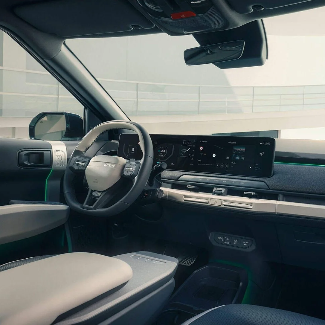 Interno di un'auto moderna con un volante, un cruscotto digitale e un grande schermo centrale.