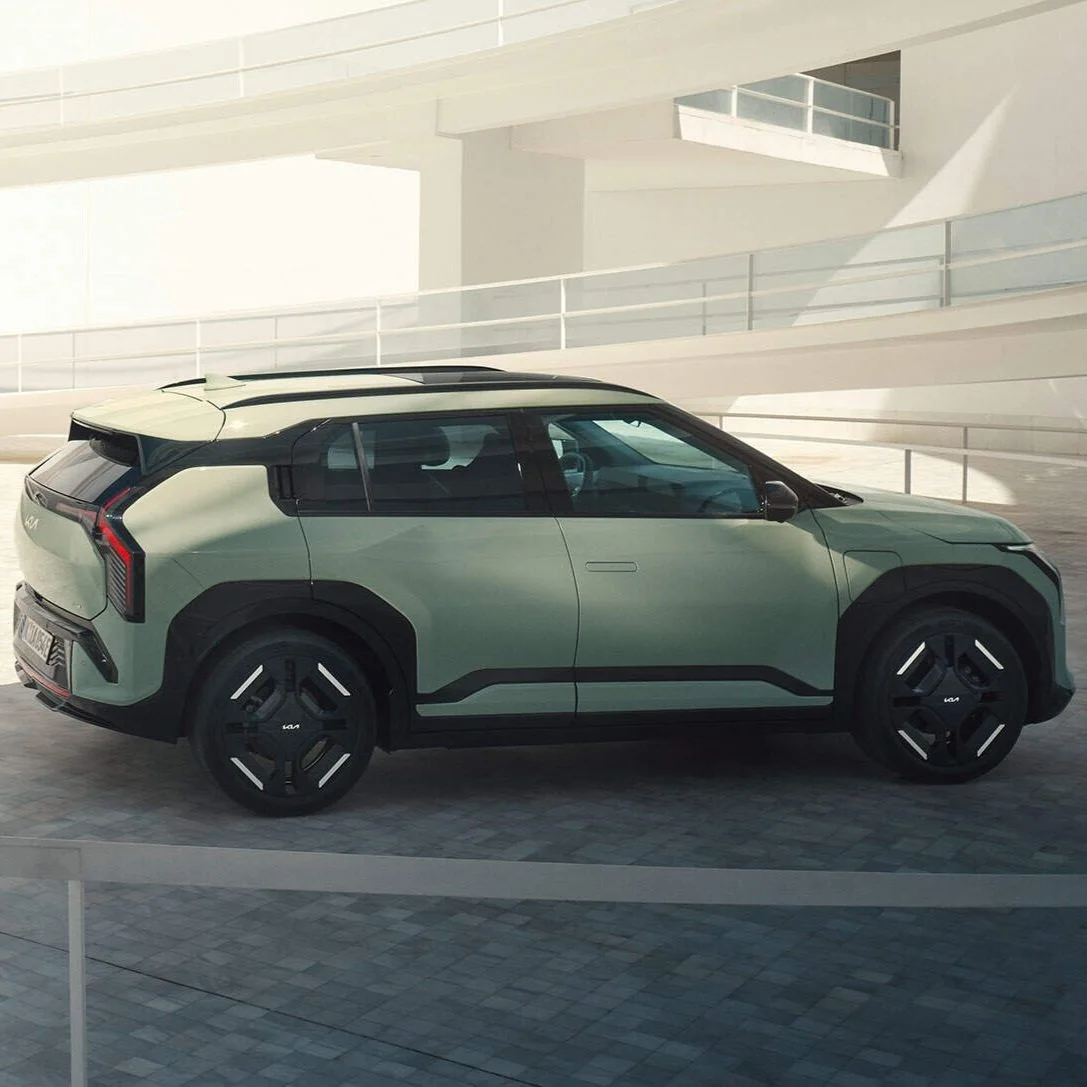 Auto elettrica di colore verde chiaro parcheggiata in un'area moderna e minimalista