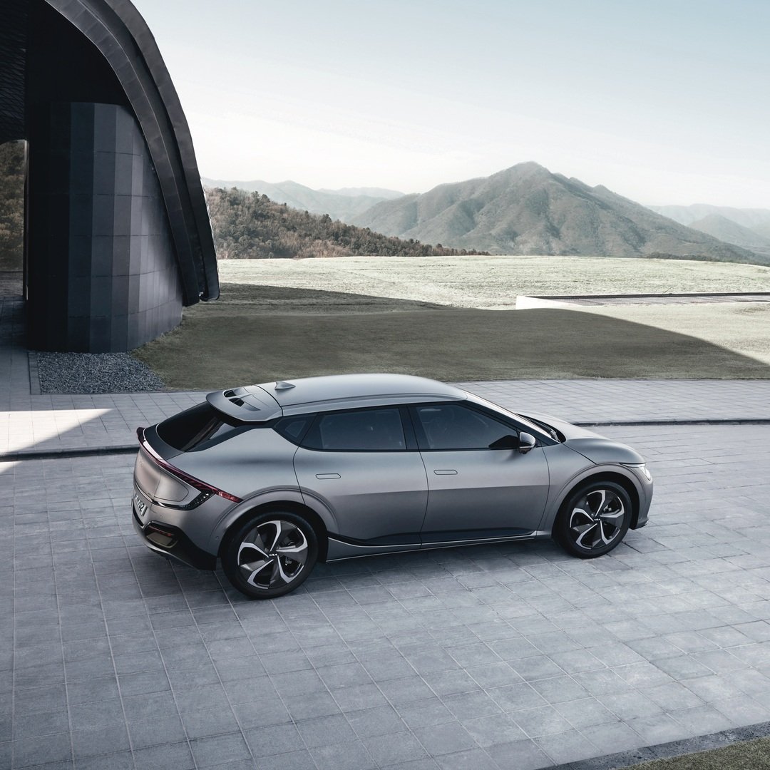 Auto ibrida di colore grigio metallizzato parcheggiata davanti a un edificio con paesaggi montani sullo sfondo.