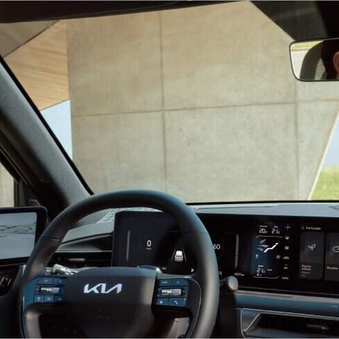 Interno di una vettura Kia con volante, display digitale e strumenti di bordo.