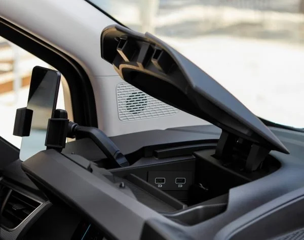 Interno di un'auto con dispositivi tecnologici come uno schermo e porte USB visibili nella console