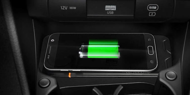 Smartphone in car or charging dock with a fully charged green battery icon on screen.
