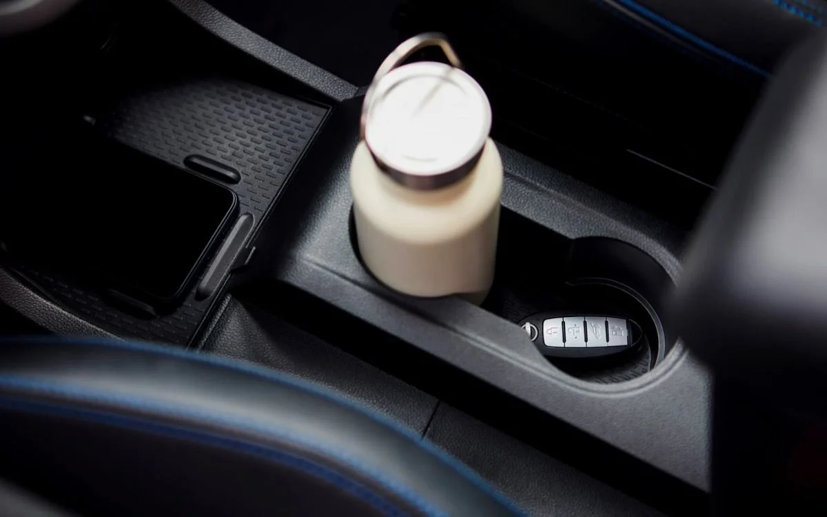 Interno di un'auto con una bottiglia e un portafoglio sulla console centrale