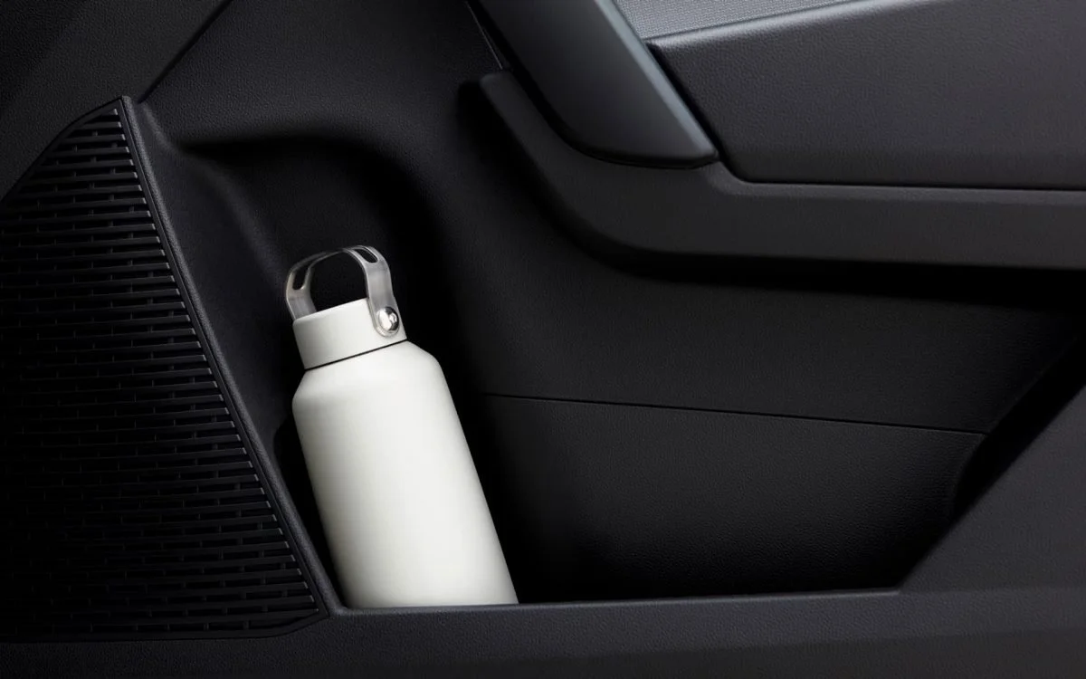 Una bottiglia d'acqua bianca inserita nello scomparto laterale di un'auto.
