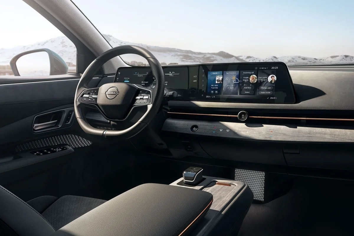 Interno di un'auto moderna con volante, dashboard digitale e display centrale widescreen con varie funzionalità.