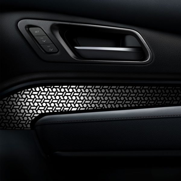 Dettaglio dell'interno di un'auto con maniglia e un elemento decorativo a motivi geometrici.