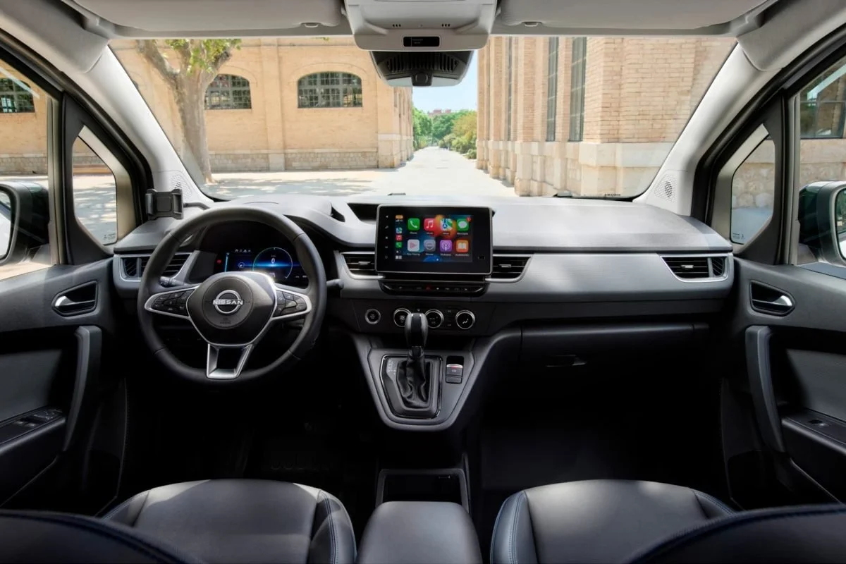 Interno di un'auto Nissan con lavagna digitale al centro e volante con logo Nissan.