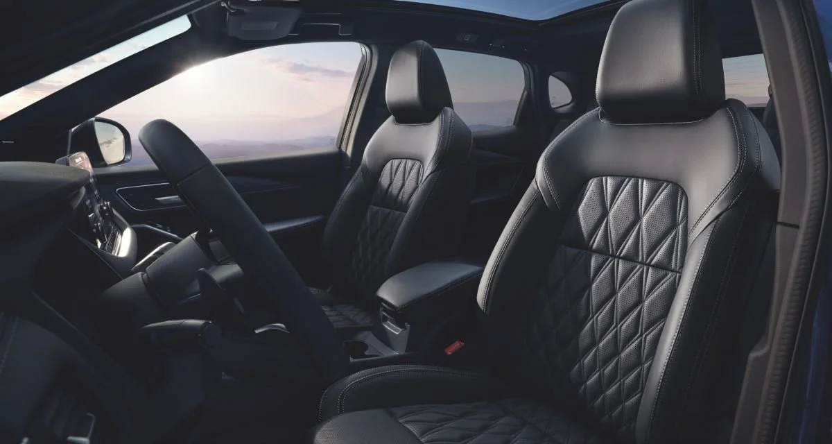 Interno di un'auto di lusso con sedili in pelle nera e dettagli cuciti a diamante.