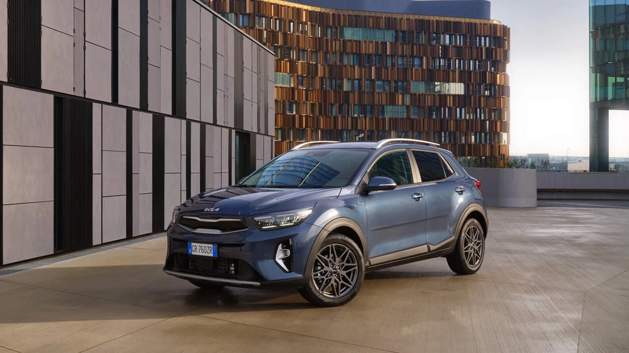 Un'auto SUV moderna grigia parcheggiata in una zona urbana con edifici di design contemporaneo sullo sfondo.