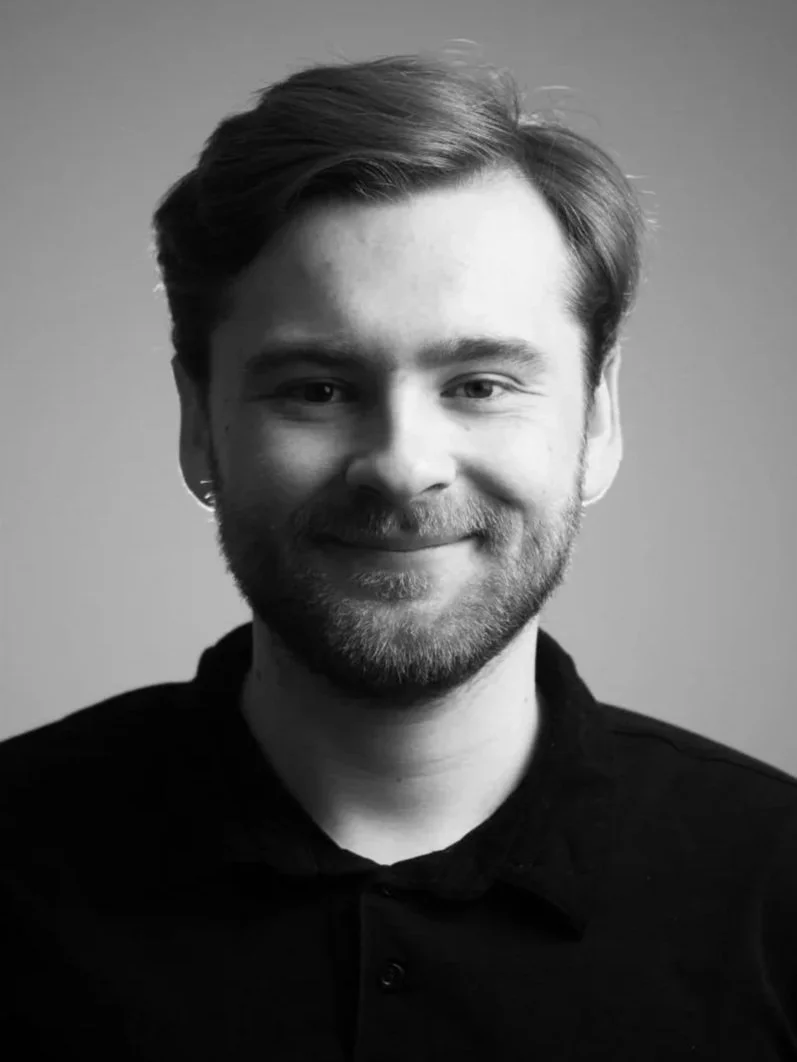 Black-and-white portrait of Wilhelm Schenk, Director and Producer at Black Lab Media, photographed in a studio setting.