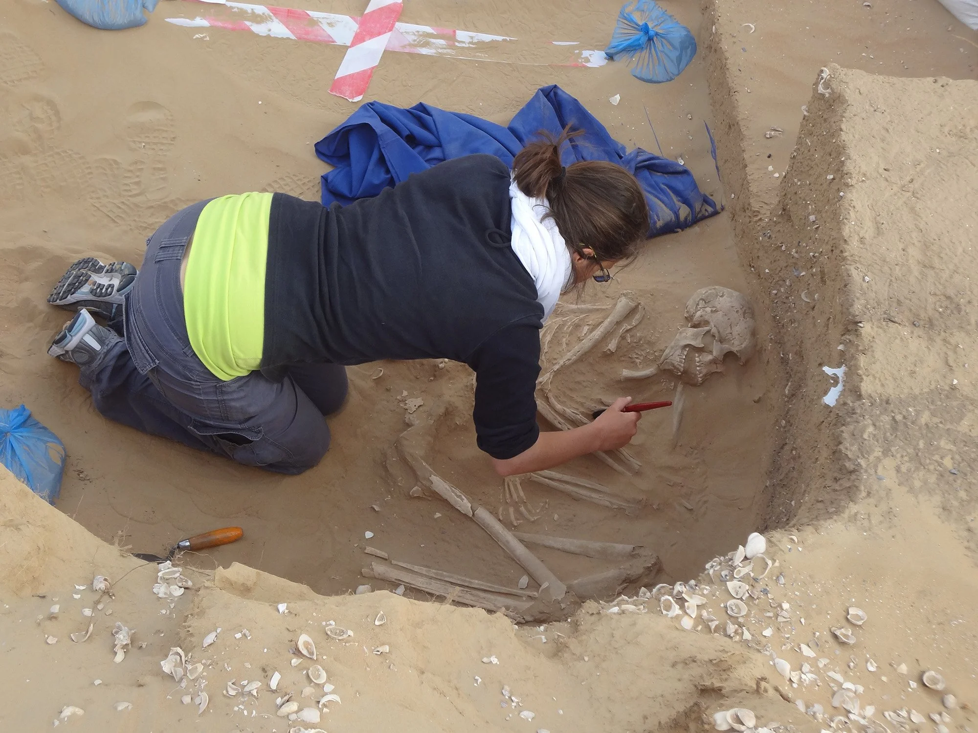 Archaeologist carefully excavating a human burial on site